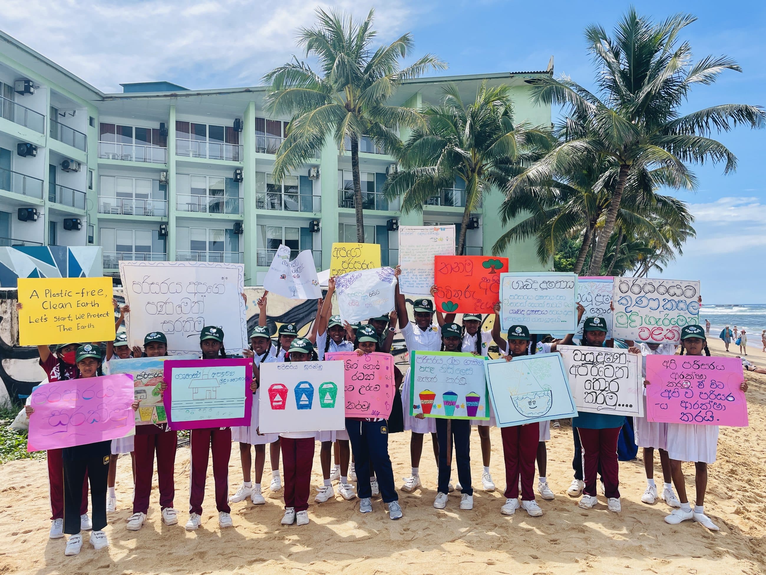 Schoolchildren holding up hand-made awareness banners on the beach after an NRC school programme.